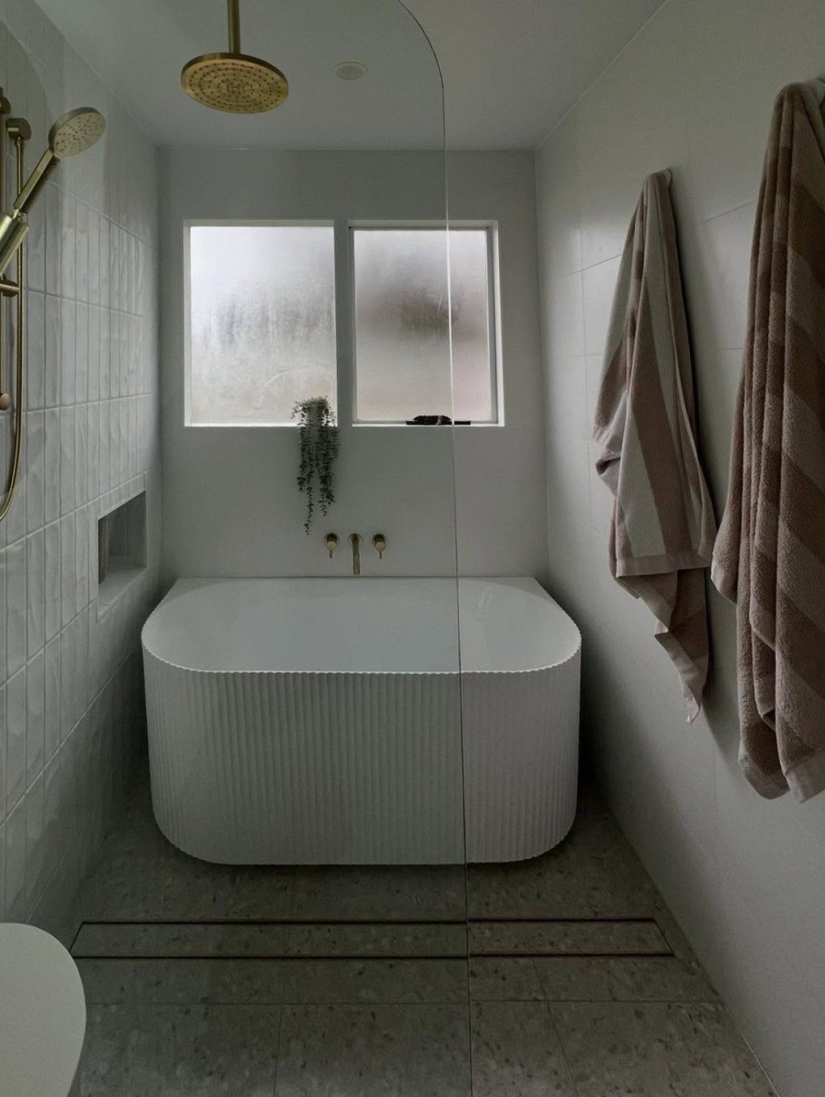 Renovated bathroom with a freestanding bath, brass wall spout and overhead shower, fitted off by Custom Plumbing Group